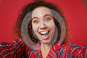 Close up of excited young african american girl in pajamas homewear rest at home isolated on red background. Relax good