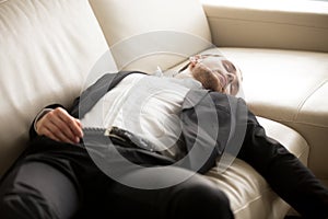 Close up of exhausted businessman laying on the couch.