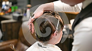 Close-up of experienced barber using comb and scissors to cut extra hair.