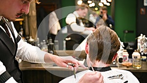 Close-up of experienced barber using comb and scissors to cut extra hair.