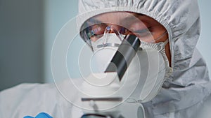 Close up of experienced biologist in ppe suit working on microscopes