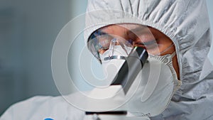 Close up of experienced biologist in ppe suit working on microscopes