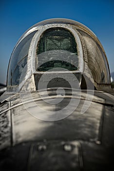 Close-up of an exterior of an old fighter jet cockpit against a clear sky