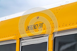 Close up of the exterior of a yellow school bus with an Emergency Exit sign