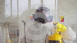 Close up exterminator in overalls carries out surface treatment by means of a spray