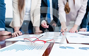 Close-up of eyeglasses during a meeting of business analysts