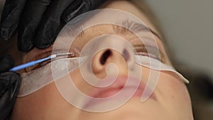 Close-up of eyelash care treatment procedures. Beautiful female, blond hair model have eyelashes lamination. Woman doing