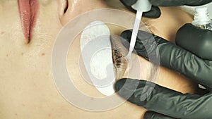 Close-up of eyelashes application on eyelashes of a special fluid for further procedures in a beauty salon