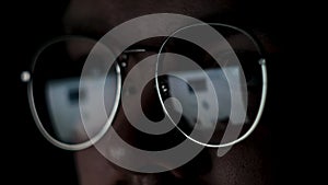 Close up of the eyes of a man with glasses at the computer isolated on black background. Concept. The reflection of the