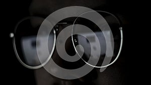 Close up of the eyes of a man with glasses at the computer isolated on black background. Concept. The reflection of the