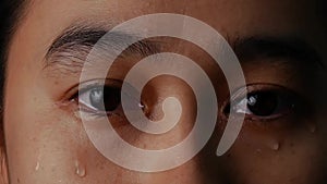 Close up eyes of woman crying with tear on black background.