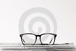 close up of eyewear on pile of newspapers, on white background with copy space