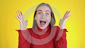 Close-up face of amazed woman shocked. Handsome girl surprised to camera over yellow background.