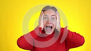 Close-up face of amazed woman shocked. Handsome girl surprised to camera over yellow background.