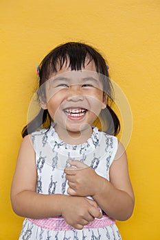 close up face of asian ked toothy smiling facial face with happiness emotion on yellow wall use for children lovely emotion and d