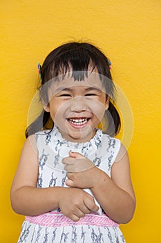 Close up face of asian kid toothy smiling facial face with happiness emotion on yellow wall use for children lovely emotion and de