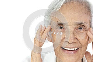 Close-up,Face of asian senior woman applying eye cream,anti-aging,nourishing under eye,facial treatment,happy smiling old elderly