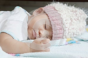 Close up face of baby sleeping on clothes bed wearing wool hood