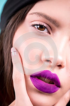 Close up face of a beautiful young brunette woman with professional makeup, well groomed face, purple lips. Fashion, cosmetics, fa