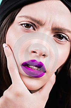 Close up face of a beautiful young brunette woman with professional makeup, well groomed face, purple lips. Fashion, cosmetics, fa