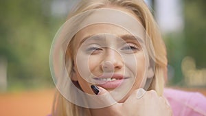 Close-up face of blond young woman with grey eyes smiling at camera. Portrait of charming beautiful Caucasian lady