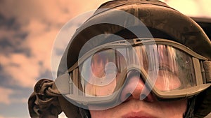 Close-up face of caucasian soldier in helmet with sky and sunshine reflection on glasses looking ahead, vibes of hope