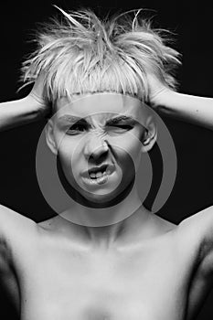 Close up on face of crazy mad cocky young woman with stylish dyed pink hair, hands ruffle her haircut angry and bold