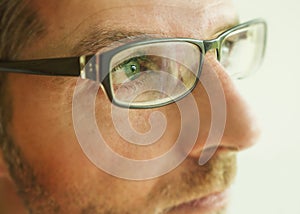 Close up face crop portrait of man in glasses looking thoughtful and serious in studio on a light background