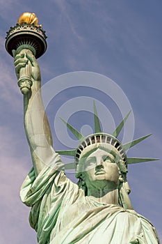 Close-up of the face, crown and hand holding the torch of the Statue of Liberty on a sunny day