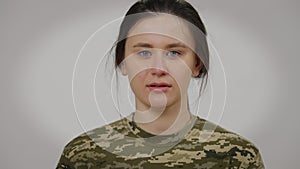 Close-up face of crying female soldier looking at camera. Headshot portrait of sad depressed stressed Caucasian young