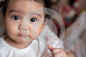 Close up face of cute Asian baby girl with mouth soiled food after eating, looking at camera