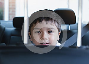 Close up face of cute boy siting in safety car seat looking out with smiling face,Child sitting in the back passenger seat with a
