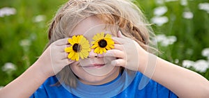 Close up face of cute child outdoors. Spring banner for website header. Spring kid. Funny little boy with daisy in eyes.