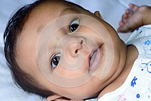 Close up face of cute newborn baby boy smiling in happy mood posing at camera. One month old Sweet little infant toddler Closeup