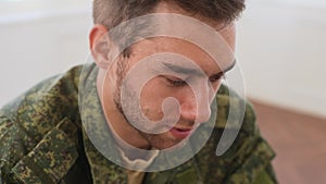 Close-up face of depressed Caucasian male veteran in camouflage uniform talking about trauma in PTSD support group, slow