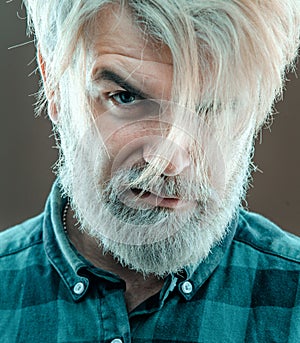 Close up face of fashionable latin man on grey background. Guy with beard and modern hairstyle in the studio.