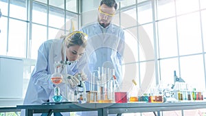 Close up face of female scientist seeing microscope. Man Research is working in the Laboratory. With foreground of tube and Beaker