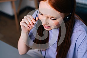Close-up face of friendly young woman operator using headset and laptop computer during customer support.