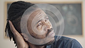Close-up face of handsome young African American man thinking indoors. Headshot portrait of thoughtful confident guy