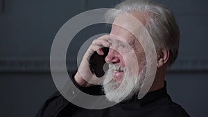 Close-up face of happy bearded mature adult man with tears in eyes talking on mobile phone with family.