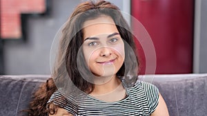 Close-up face of happy beautiful fresh young woman with pure skin and curly hair looking at camera