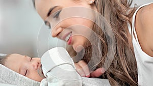 Close-up face of happy mother kissing her little sleeping baby admiring and having positive emotion