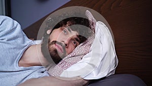 Close-up face of happy sleeping young man opening eyes, waking up and smiling looking away.