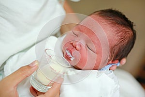 Close-up face of infant drinking milk from glass cup