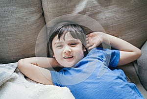 Close up face of kid looking at camera with smiling, A happy boy lying on sofa relaxing on weekend, Comfortable Child laying down