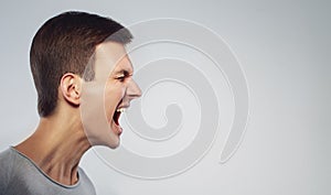 Close up face of man shouting with anger. Cry and stand in profile. on grey background. Copy space.