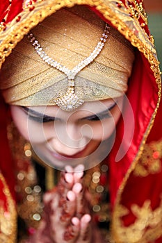 Close up of face portrait of Asian woman wearing traditional Minangkabau dress bowing with hands put together in wedding ceremony