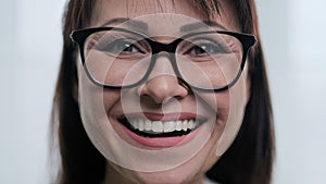 Close-up face portrait of beautiful mature woman with glasses smiling with teeth