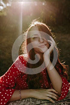 Close up face portrait beauty caucasian white woman with red long curly hair dressed in red shirt holding her head by hand and