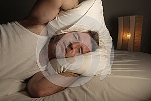 Close up face portrait of sleepless and awake attractive man with eyes wide open at night lying on bed suffering insomnia sleeping